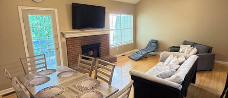 A spacious living area with a dining table, sofas, and ceiling fans.