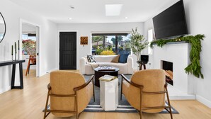 A modern living room with a sofa, two armchairs, a coffee table, a flat-screen TV, a fireplace, and a view through a glass door. - Unique Downtown LA Gem: World Cup, SoFi, Gym & Games - 2 suites (Los Angeles)