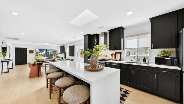 A modern kitchen with a large island, black cabinets, and a view to the outside. - Unique Downtown LA Gem: World Cup, SoFi, Gym & Games - 2 suites (Los Angeles)