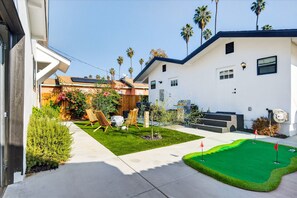 A residential property with a well-maintained lawn, a small garden with flowers, and a patio area with outdoor furniture. - Unique Downtown LA Gem: World Cup, SoFi, Gym & Games - 2 suites (Los Angeles)