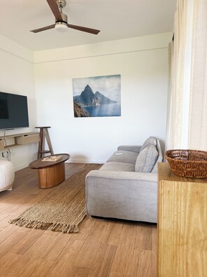 A living room with a grey sofa, wooden coffee table, and a large flat-screen TV.