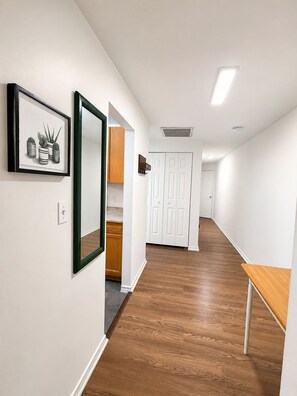 A hallway with wooden flooring, white walls, a framed picture, and a door at the end. - Entire home near Capitol Hill! (Washington)