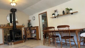 A living room with a fireplace, wooden chairs, a dining table, and shelves with plants. - Family-Friendly 3bdr Coastal Retreat Near Beaches & Redwoods (Watsonville)