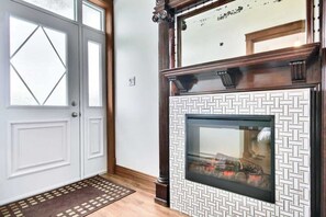 Ein Zimmer mit Kamin, einer weißen Tür mit Glasfenstern und einer Wand mit Muster.