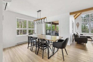 Un comedor moderno con una mesa de madera, sillas negras y una lámpara colgante.