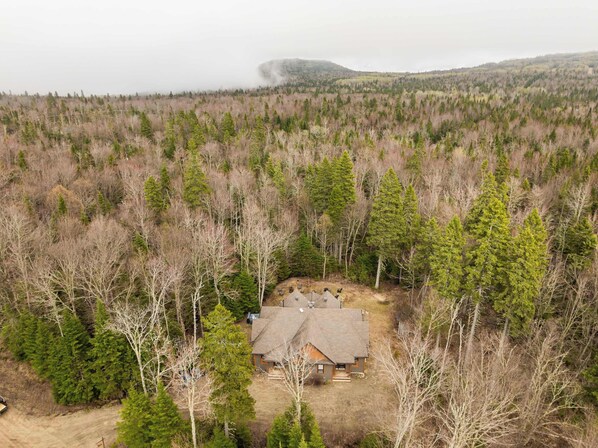 A house surrounded by dense forest, with a clear view of the surrounding hills.