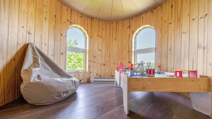 A room with wooden walls, two windows, a bean bag chair, and a table with toys. - Chateau De Valvak  Spa & BBQ  Free Parking (Lévis)