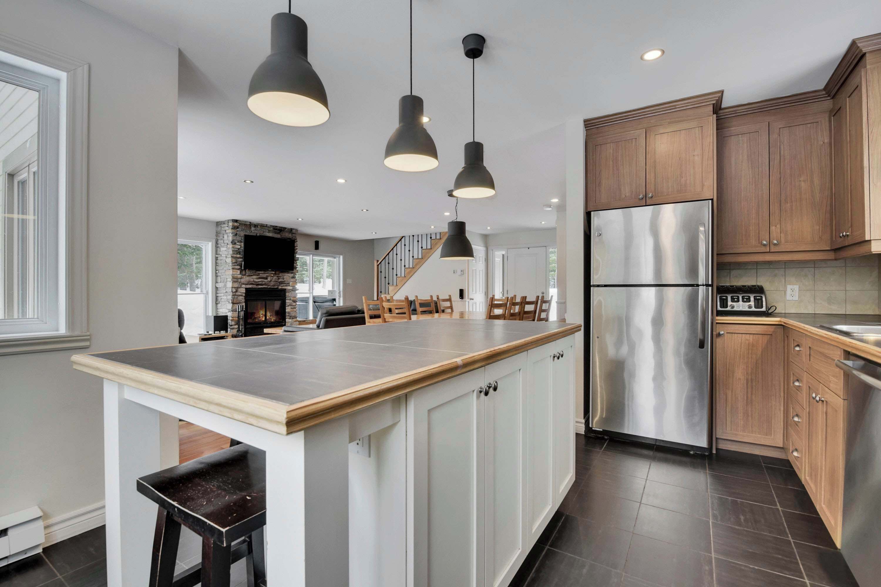 A modern kitchen with a central island, stainless steel appliances, and pendant lighting.