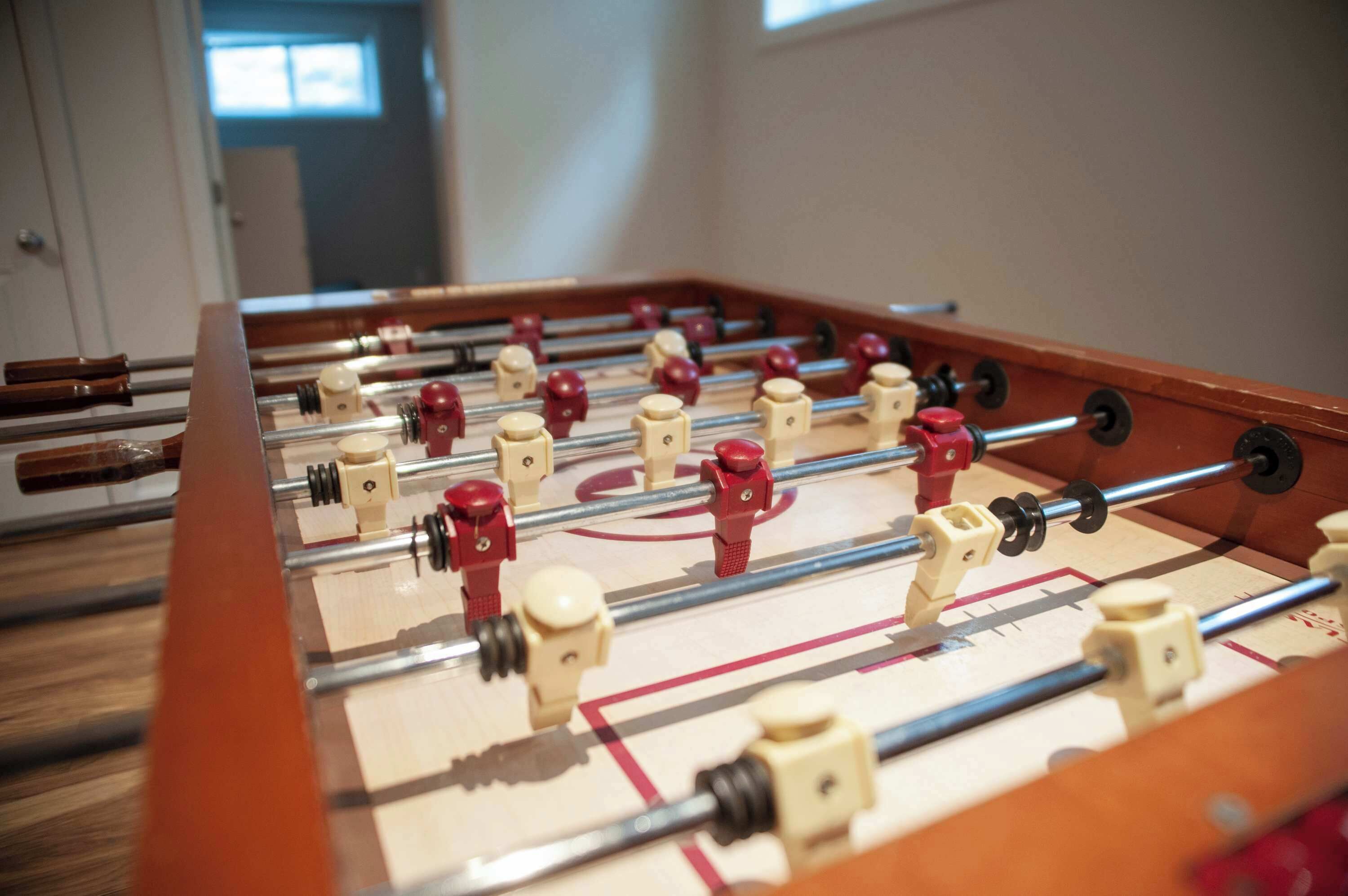 Ein Kicker mit roten und weißen Spielfiguren, einem Holzrahmen und Metallstangen.