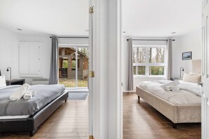 Un dormitorio con dos camas, una puerta corrediza de vidrio a una terraza y vistas a una cabaña de madera.