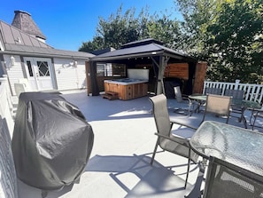 Un'area patio coperta con posti a sedere all'aperto, una vasca idromassaggio e un pontile in legno.