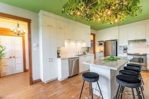 A modern kitchen with white cabinets, stainless steel appliances, and a central island with stools.