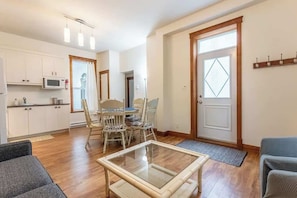Un espacio habitable compacto con comedor, kitchenette y una mesa de vidrio.