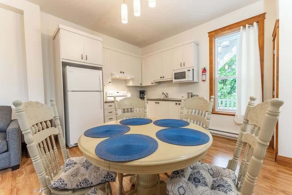 A dining area with a round table, blue placemats, and wooden chairs.