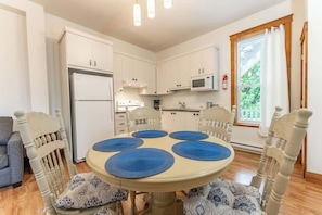 A dining area with a round table, blue placemats, and wooden chairs. - Le Juliette  Exceptional site  BBQ & Firepit (Lévis)