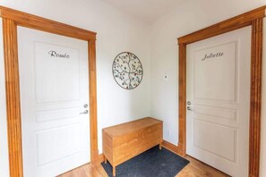 Un pasillo con dos puertas que dicen 'Roméo' y 'Juliette', un adorno circular en la pared y un banco de madera.