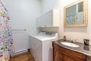 A laundry area with a washing machine, a cabinet, a mirror, and a sink. - Le Juliette  Exceptional site  BBQ & Firepit (Lévis)