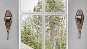 A room with a large window, a cushioned bench, and two wall-mounted decorative items.
