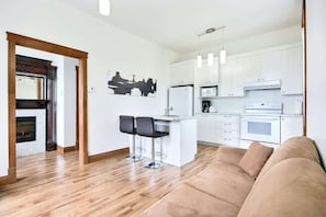 A modern kitchen with white cabinets, a central island, and bar stools.