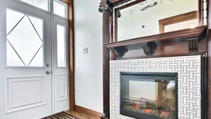 Um quarto com lareira, uma porta branca com painéis de vidro e parede estampada.