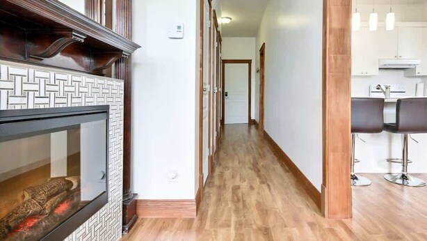 Ein Flur mit Kamin, Holzboden und einer Küchenzeile mit Barhocker.
