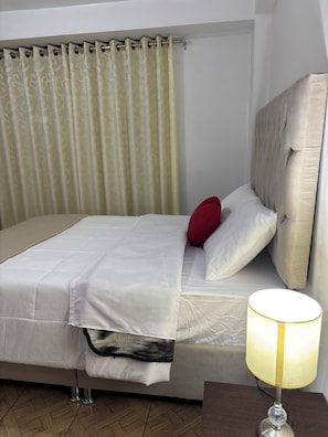 A bed with a headboard, a bedside table with a lamp, and a curtain. - Magahousecusco (Cusco)