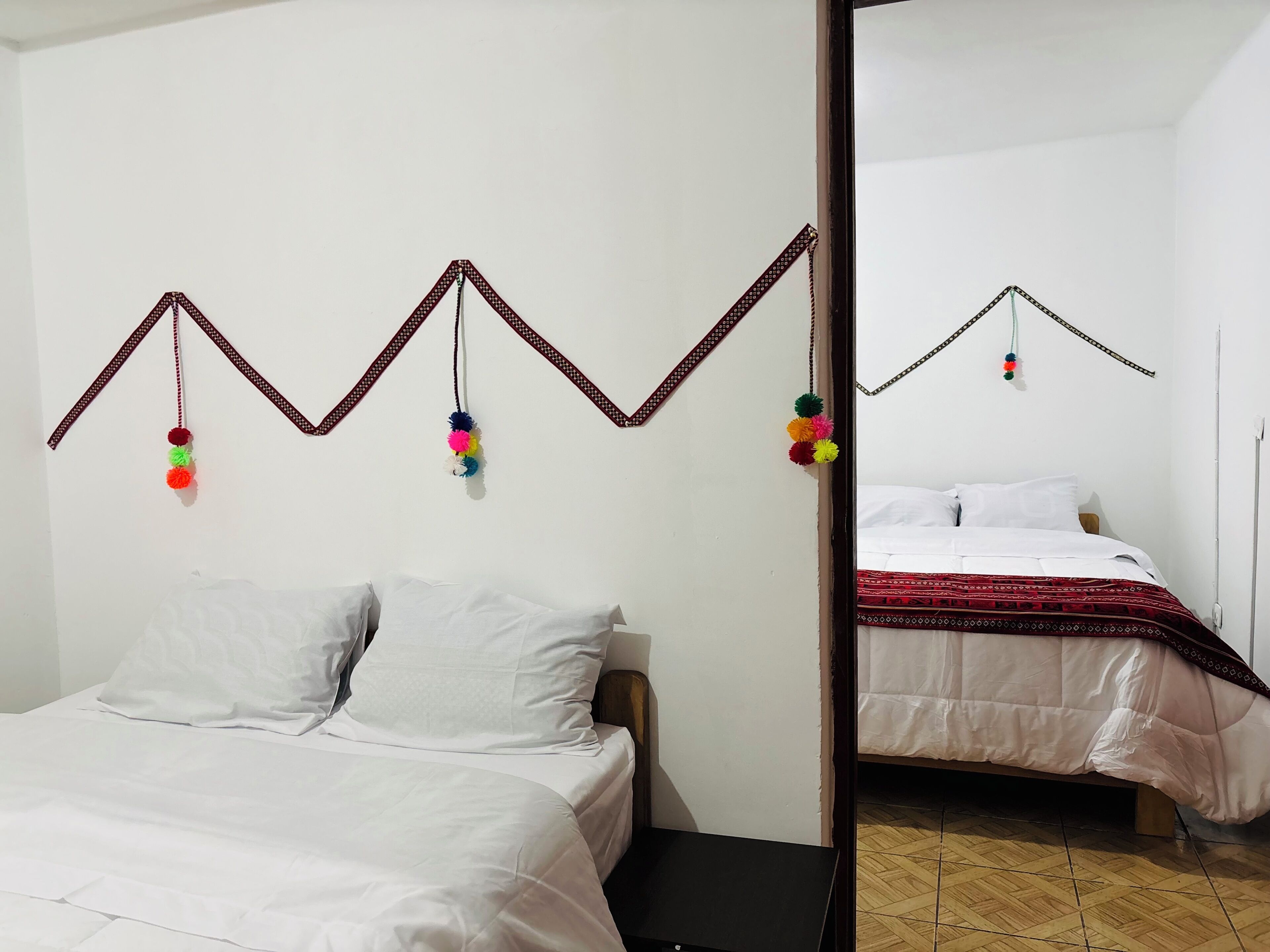 Ein Zimmer mit einem Bett, einem Spiegel und einer Wanddekoration mit herab hängenden Quasten.