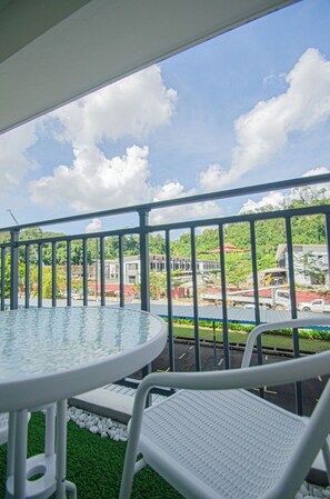 A balcony with a round table and chairs, a railing, and a view of buildings and greenery. - Trival Divine Homestay @ Sri Indah Sandakan (Sandakan)