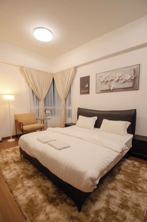 A hotel room with a large bed, a chair, a desk, a lamp, and artwork on the walls. - Trival Divine Homestay @ Sri Indah Sandakan (Sandakan)