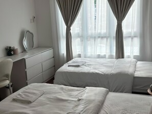 A hotel room with two beds, a desk, a mirror, and a window with curtains. - Trival Divine Homestay @ Sri Indah Sandakan (Sandakan)