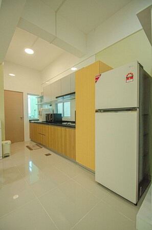 A modern kitchen with white cabinets, a stainless steel refrigerator, and a microwave. - Trival Divine Homestay @ Sri Indah Sandakan (Sandakan)