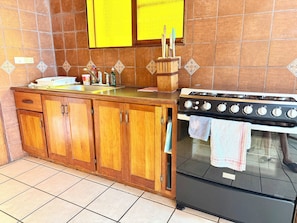 A kitchen with wooden cabinets, a stove, and a sink. - Apartment # 1 Chi-ya, San Juan laguna (San Juan la laguna)