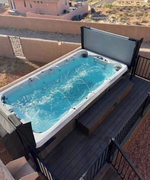 Un bain à remous sur une terrasse en bois, avec vue sur un paysage désertique.