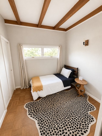 A bedroom with a bed, a window, a wooden ceiling, a small round table, and a leopard print rug.. 15 Mins to CWS - Charles Schwab Field!