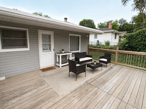 A deck with outdoor furniture, a door with a 'hello' mat, and a small table with a plant.