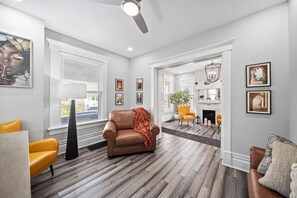 Una sala de estar con un sofá de cuero marrón, un sillón amarillo y una chimenea.