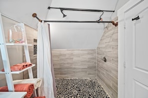 A shower with a black and white patterned floor, a towel rack with towels, and a shower curtain. - THE OAKWOOD!! Beautiful Historic 4BR Home Near Nationwide Children’s (Columbus)