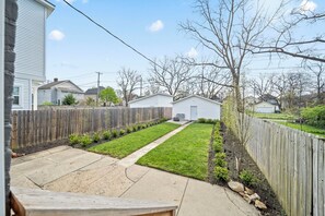 A residential backyard with a wooden fence, a lawn, and a pathway leading to a garage. - THE OAKWOOD!! Beautiful Historic 4BR Home Near Nationwide Children’s (Columbus)