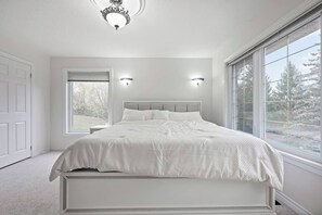 Una camera da letto con un letto grande, due applique, una plafoniera, una finestra e una porta.