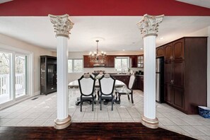 Una cocina amplia con armarios de madera oscura, una isla central y un comedor con candelabro.