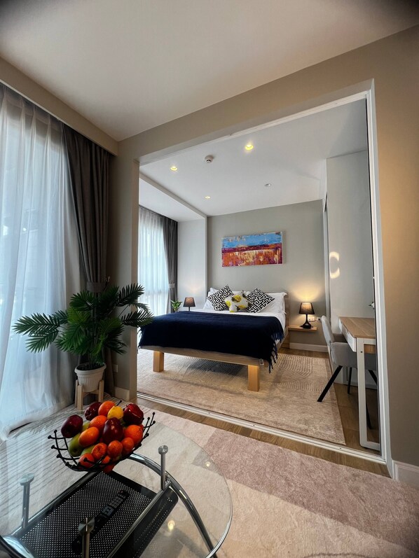 A modern hotel room with a bed, bedside table, lamp, and a desk. - Diamond Resort 1 bedroom (Tambon Choeng Thale)
