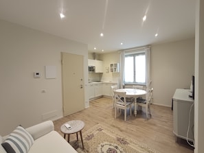 A compact living space with a dining area, kitchenette, and a small seating area with a patterned rug. - Antica_Stresa_1_apartment (Stresa)