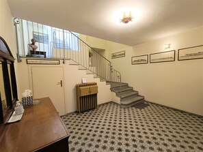 Un escalier avec une rampe en métal, un radiateur et des carreaux de sol à motifs.