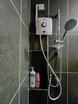 Een douche met een handdouche, een bedieningspaneel aan de muur en een plank met twee flessen shampoo en conditioner.