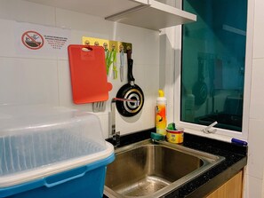 A kitchen with a stainless steel sink, a red cutting board, a green-handled knife, and a bottle of dish soap. - Trival Lavender Homestay @ Sri Indah Sandakan (Sandakan)