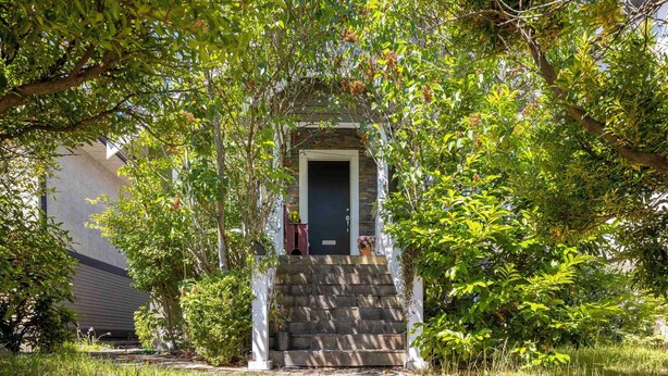 Uma casa com varanda da frente, degraus que levam à porta e um jardim.