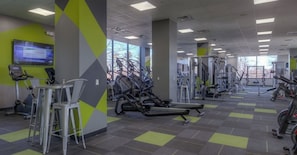 Ein Fitnessraum mit Trainingsgeräten, einem Fernseher und einer Sitzecke.