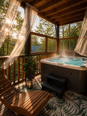 Un bain à remous sur une terrasse en bois, avec vue sur les arbres et un plan d’eau.