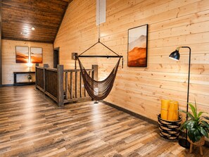 A wooden interior with a hammock, a lamp, and a plant. - Luxury Group Retreat Gatlinburg with Indoor Pool, Hot Tub, Theatre, Pickle Ball (Pigeon Forge)