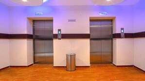 Un hall de hotel con dos ascensores, un basurero y un letrero que indica la ubicación.
